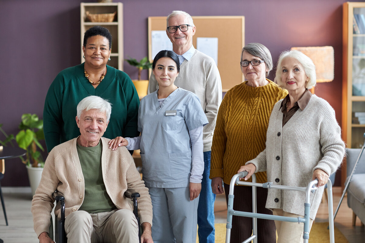Small intimate group photo showing 5 residents with caring staff member
